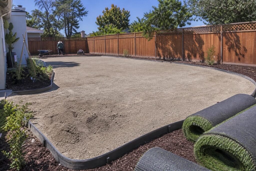 Prepared base layer and artificial turf rolls ready for installation in a San Martin backyard