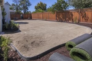 Prepared base layer and artificial turf rolls ready for installation in a San Martin backyard